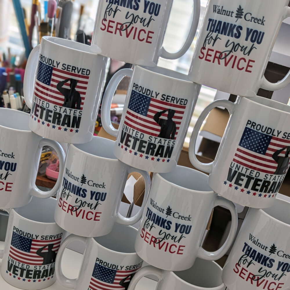 A number of printed veterans day mugs stacked on top of each other.