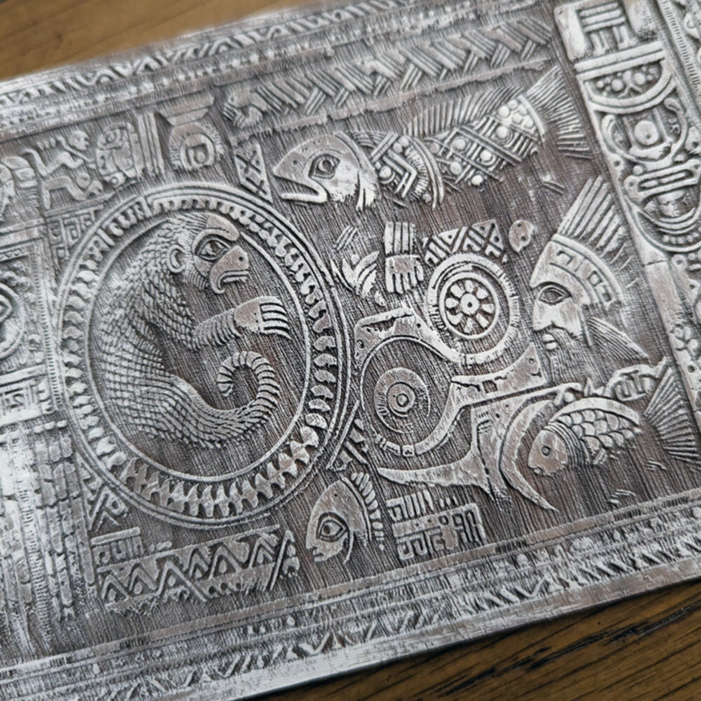 A laser etched piece of wood with a number of shapes & symbols, etched in Walnut and whitewashed