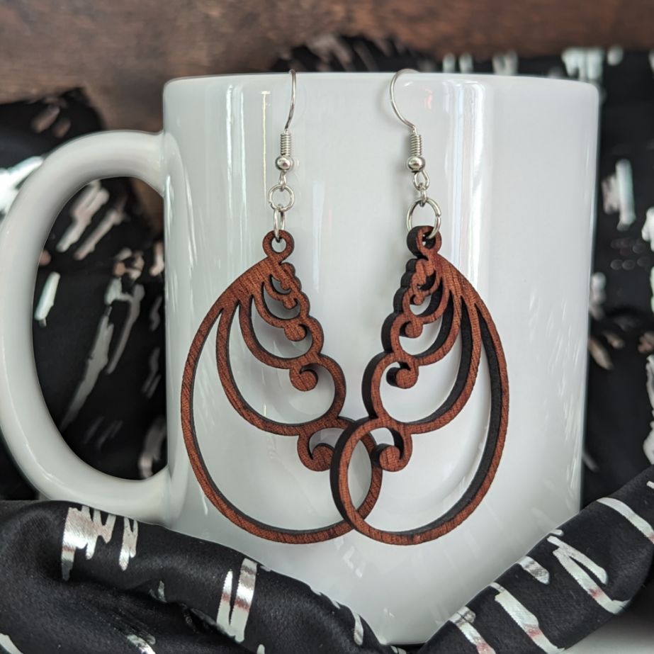 Earrings with swirl details, hanging from a white porcelain mug