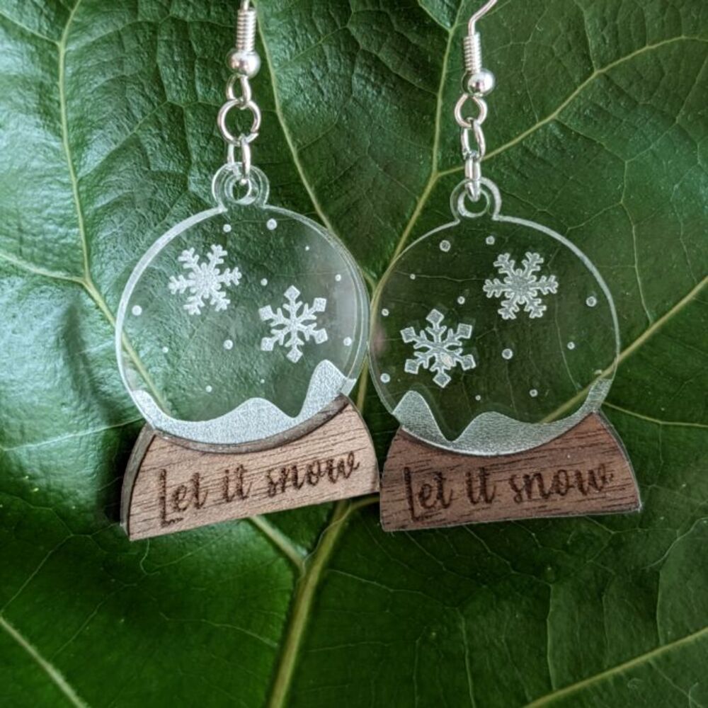 Snow globe earrings against a green leaf