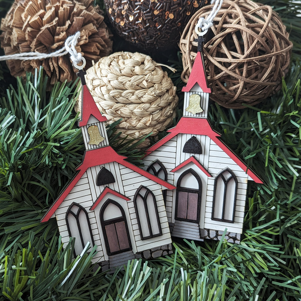 Two Christmas ornament in the shape of a little white chapel with red roof.
