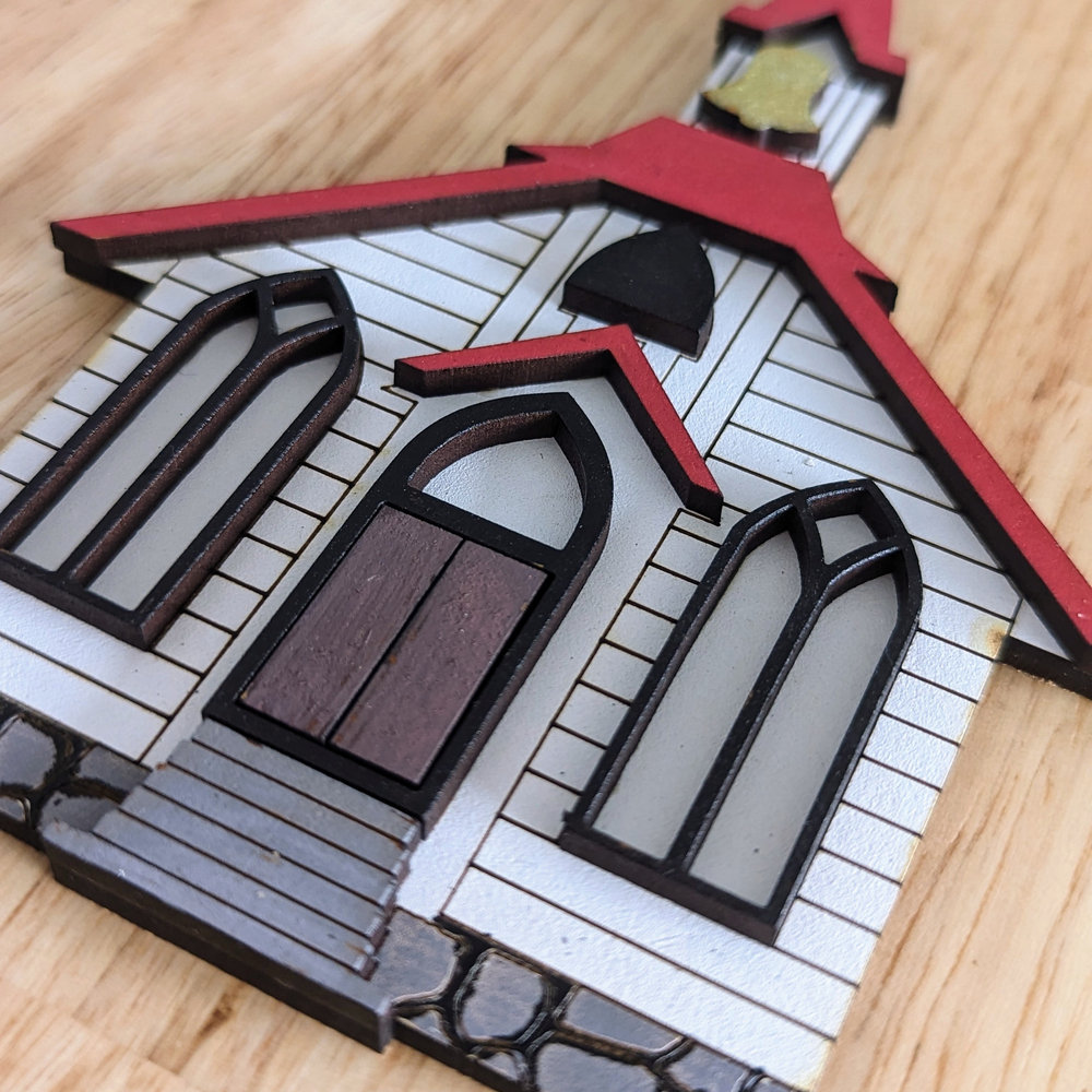 A Christmas ornament in the shape of a little white chapel with red roof.