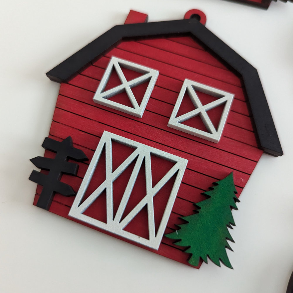 A Christmas Ornament that looks like a Red Barn with wooden slates and a black roofline.