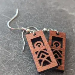Rectangular mandala earrings cut from sapele wood against a dark granite