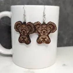 A koala bear with hearts earring engraved on a sapele wood against a white porcelain mug