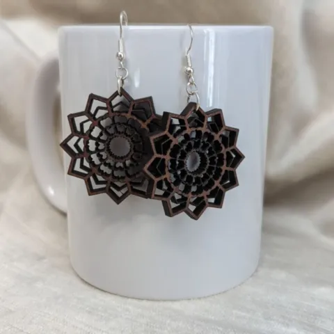 A mandala design earring cut from Walnut wood