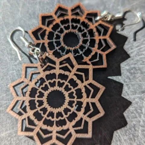 A mandala design earring cut from Walnut wood