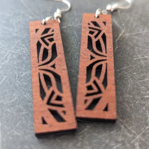 Sapele mandala earrings in front of a dark granite