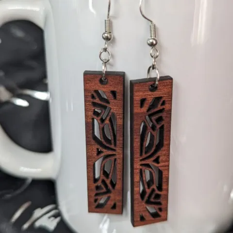 Sapele mandala earrings in front of a white porcelain mug