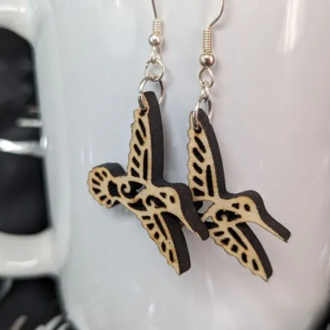 Hummingbird earrings hanging from a white porcelain mug