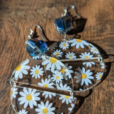 Daisy half circles earrings with bead on a wooden background