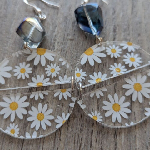 Daisy half circles earrings with bead on a light tile background