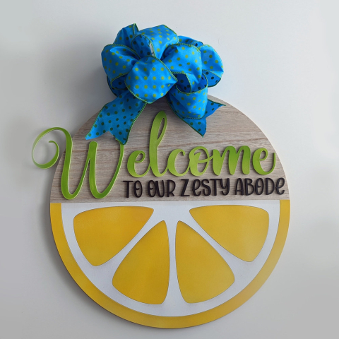 A round sign with the words "Welcome to our Zesty abode" across it. The bottom half of the sign looks as if it's a lemon cut open.