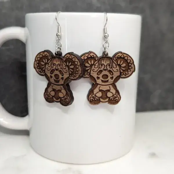 A koala bear with hearts earring engraved on a sapele wood against a white porcelain mug