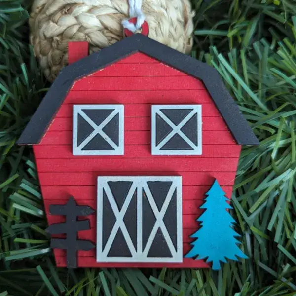 A Christmas Ornament that looks like a Red Barn with wooden slates and a black roofline.