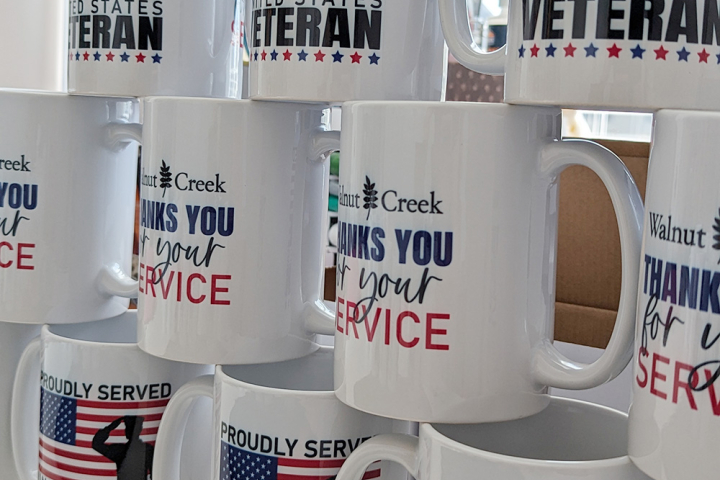 A number of printed veterans day mugs stacked on top of each other.